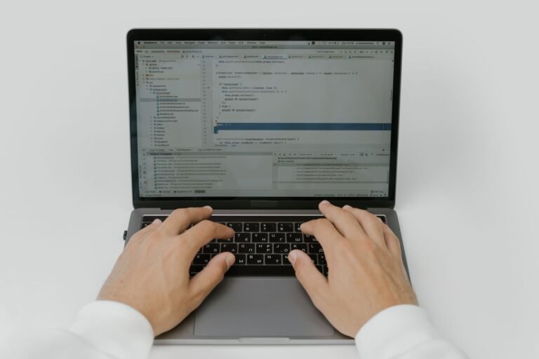 Close-up of hands coding on a laptop, showcasing software development in action.