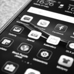Black and white photo of smartphone showing popular app icons like Facebook and WhatsApp.