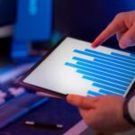 Business professional analyzing bar chart on tablet in office setting, highlighting data insights.