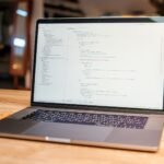 Open laptop with visible code on screen on a wooden desk in a modern, cozy workspace.