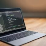 Laptop displaying software code on a wooden table, ideal for tech and programming themes.