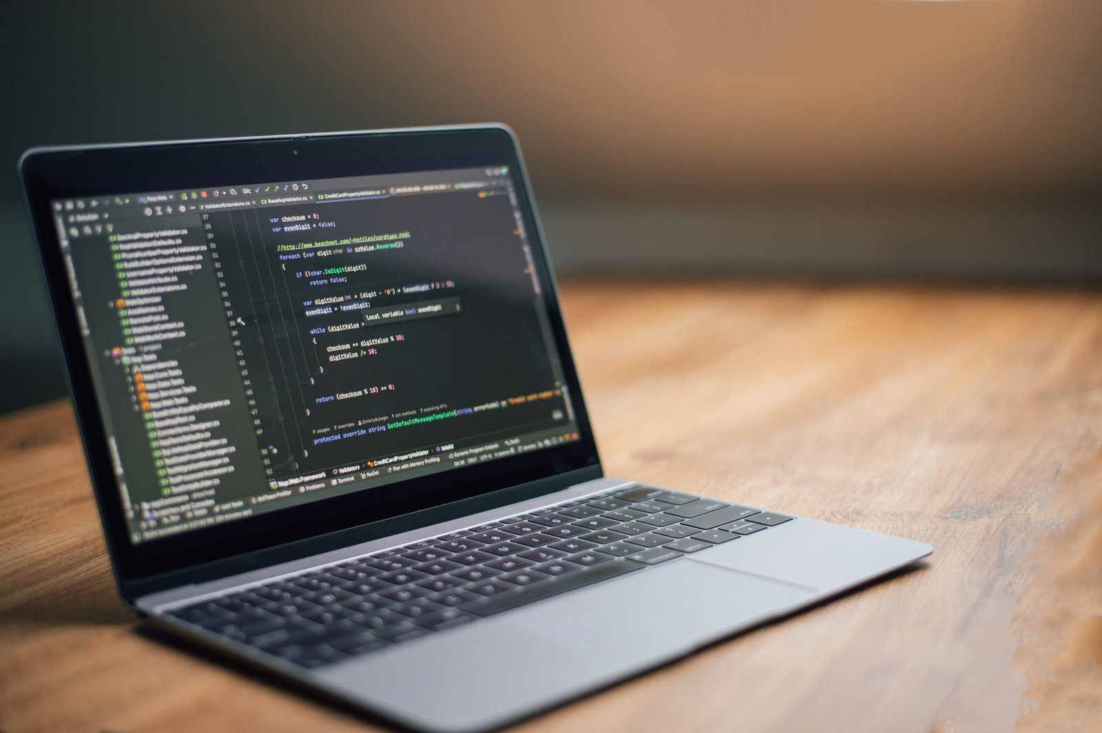 Laptop displaying software code on a wooden table, ideal for tech and programming themes.