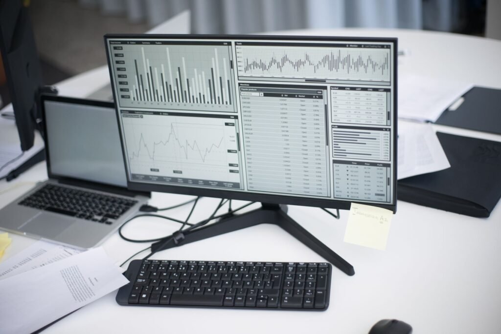 A professional workspace featuring computers and analytical graphs on a monitor, symbolizing modern business environment.