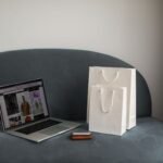 Online shopping setup with a laptop and shopping bags on a stylish couch.
