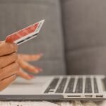 Close-up of a person using a credit card for online shopping on a laptop.
