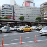 A lively street scene in Yokohama, Japan showing multiple taxis and city buildings.