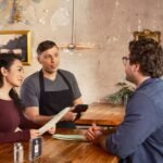 Server uses handheld POS for efficient customer service in a modern restaurant.