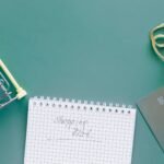 A top-down view of a shopping cart, list, card, and bag on a green background.