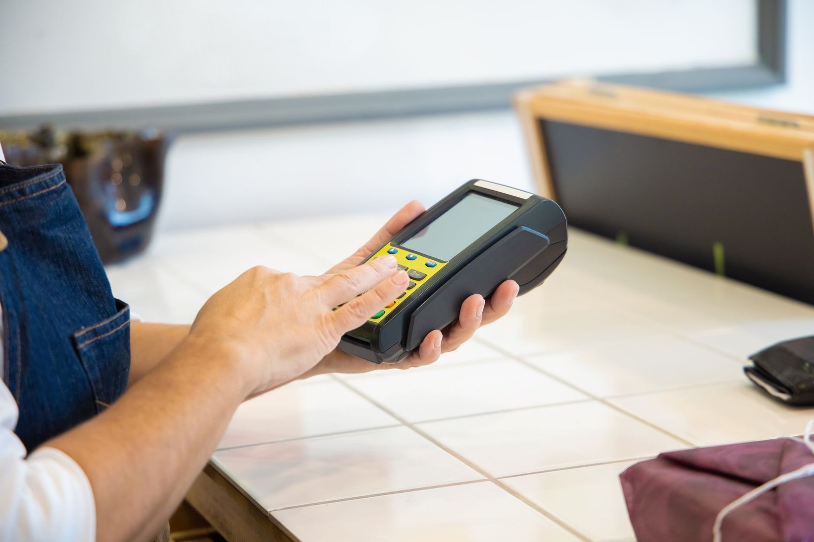 Close-up of hands using a POS machine in a retail setting, emphasizing digital payment.