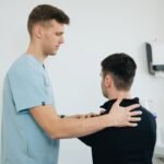 Physiotherapist working with a patient in a clinical setting, focusing on shoulder therapy.