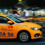 Dynamic shot of a yellow taxi speeding through city streets at night, capturing urban life.