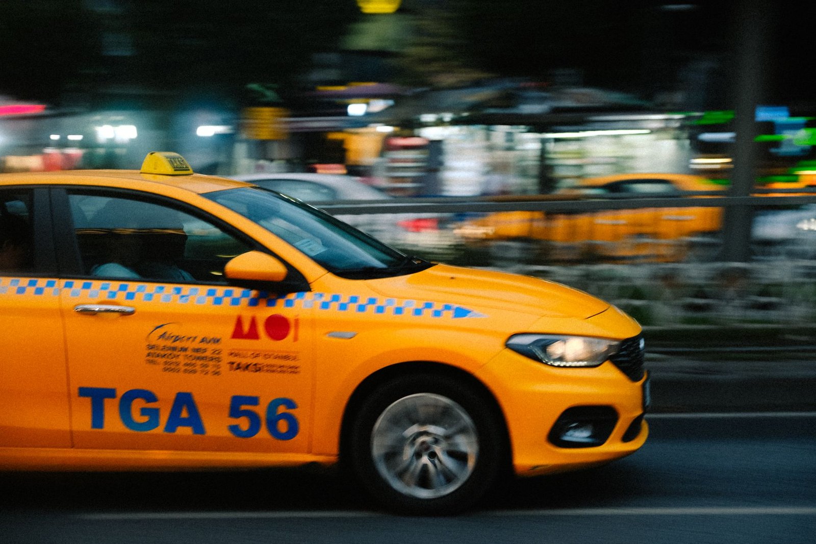 Dynamic shot of a yellow taxi speeding through city streets at night, capturing urban life.