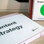 Books on content strategy and graphic design essentials resting on a wooden desk.