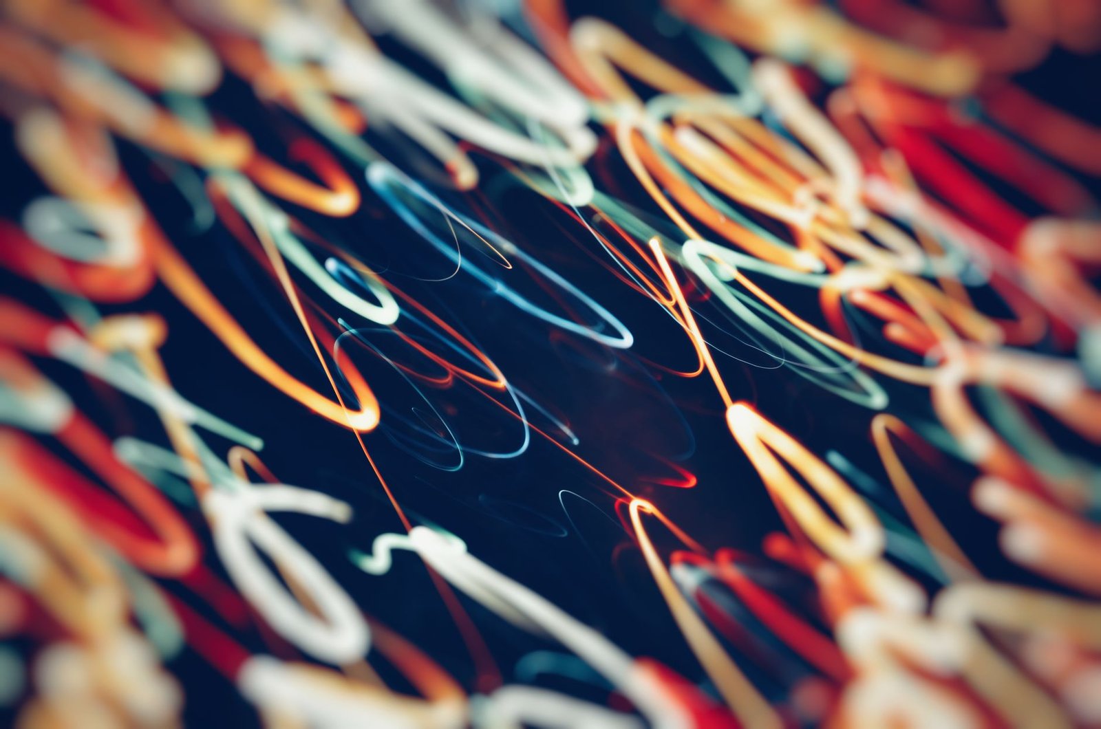 Colorful abstract neon light streaks creating vibrant motion patterns against a dark background.