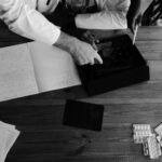 Doctors collaborating on medical research using tablets and notebooks in a monochrome setting.