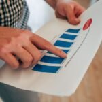 Close-up of hands pointing at a bar chart on paper, analyzing financial stats and report.