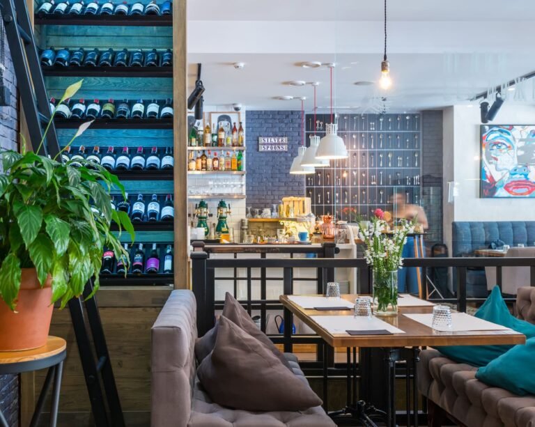 Through glass of contemporary restaurant with soft furniture and various decorative elements on shelves