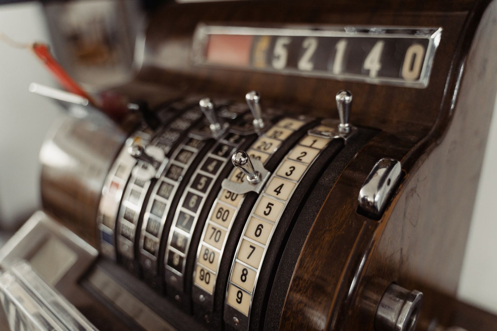 Close-up of a vintage cash register showing mechanical dials and levers.