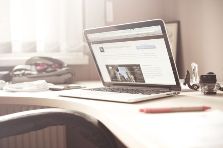 A clean and bright workspace featuring a laptop open on a wooden desk, highlighting a typical tech environment.