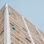 Low angle view of a modern concrete skyscraper under construction with a clear sky backdrop.