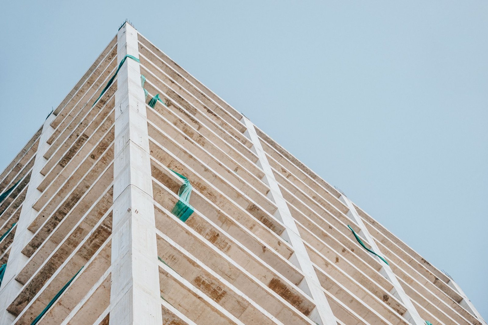 Low angle view of a modern concrete skyscraper under construction with a clear sky backdrop.