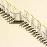 A simple outdoor metal staircase on a concrete wall casting shadows, showcasing minimalistic architecture.