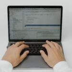 Close-up of hands coding on a laptop, showcasing software development in action.